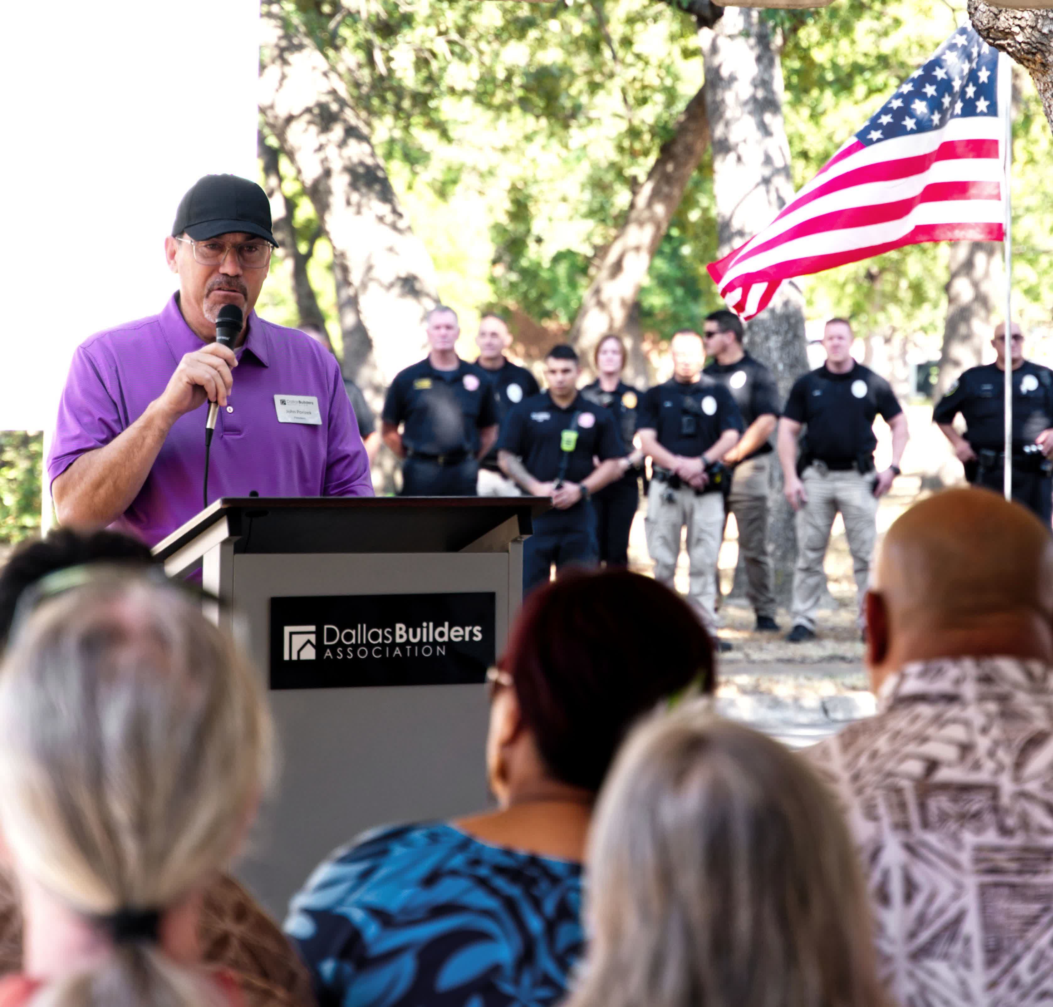 man behind a podium speaking to a crowd at a ceremony