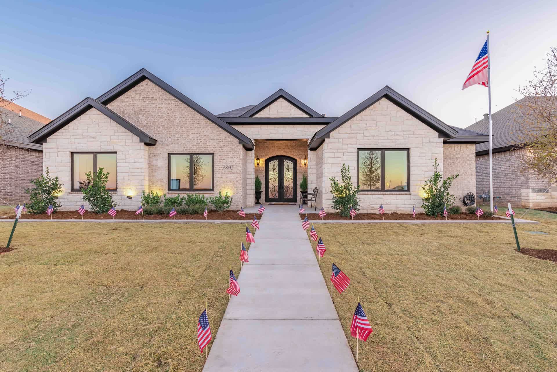 white brick home with an american flag in the yard